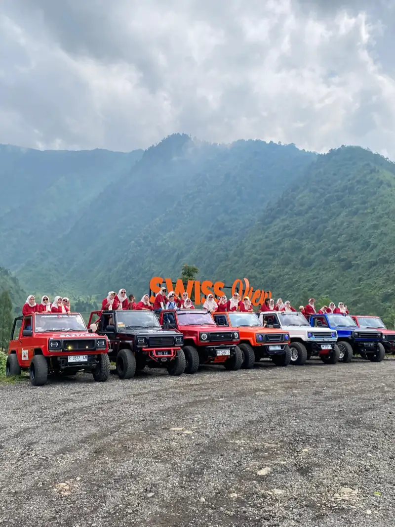 Rombongan wisatawan berseragam merah di atas tujuh jeep wisata yang berjajar di depan pegunungan